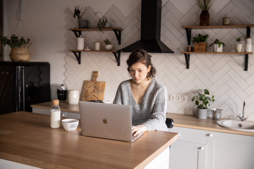 young woman browsing laptop in modern kitchen