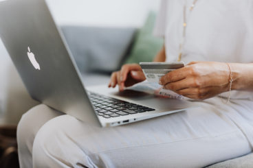 holding credit card while working on laptop