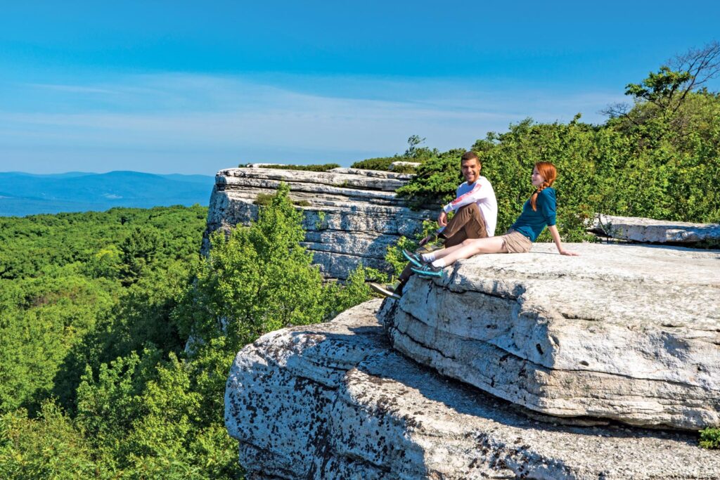 Two hikers sitting on a cliffside, enjoying the view at Sam's Point