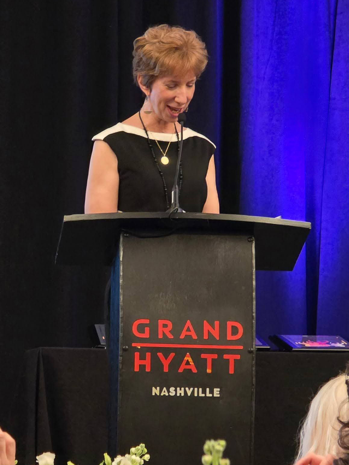 Debbe Garry at a podium speaking